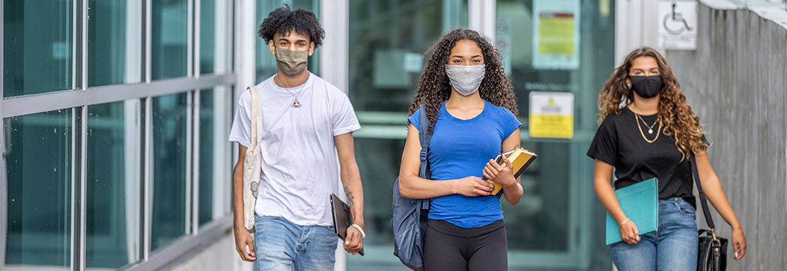 Group of students hanging out on campus together while wearing reusable face masks to protect from the transfer of germs.